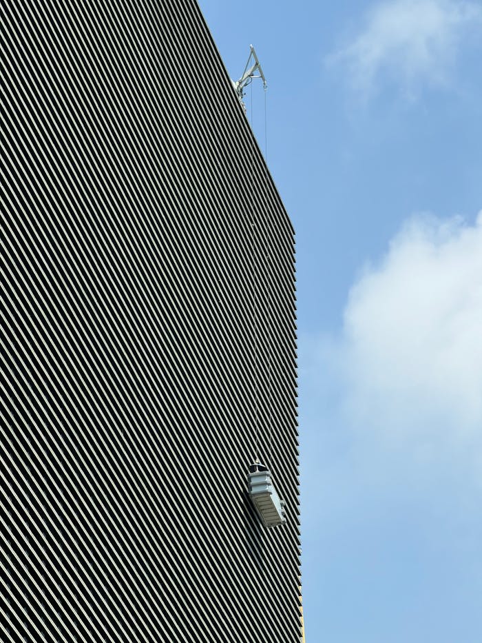 A window cleaner ascends a tall building on a clear day with blue skies.